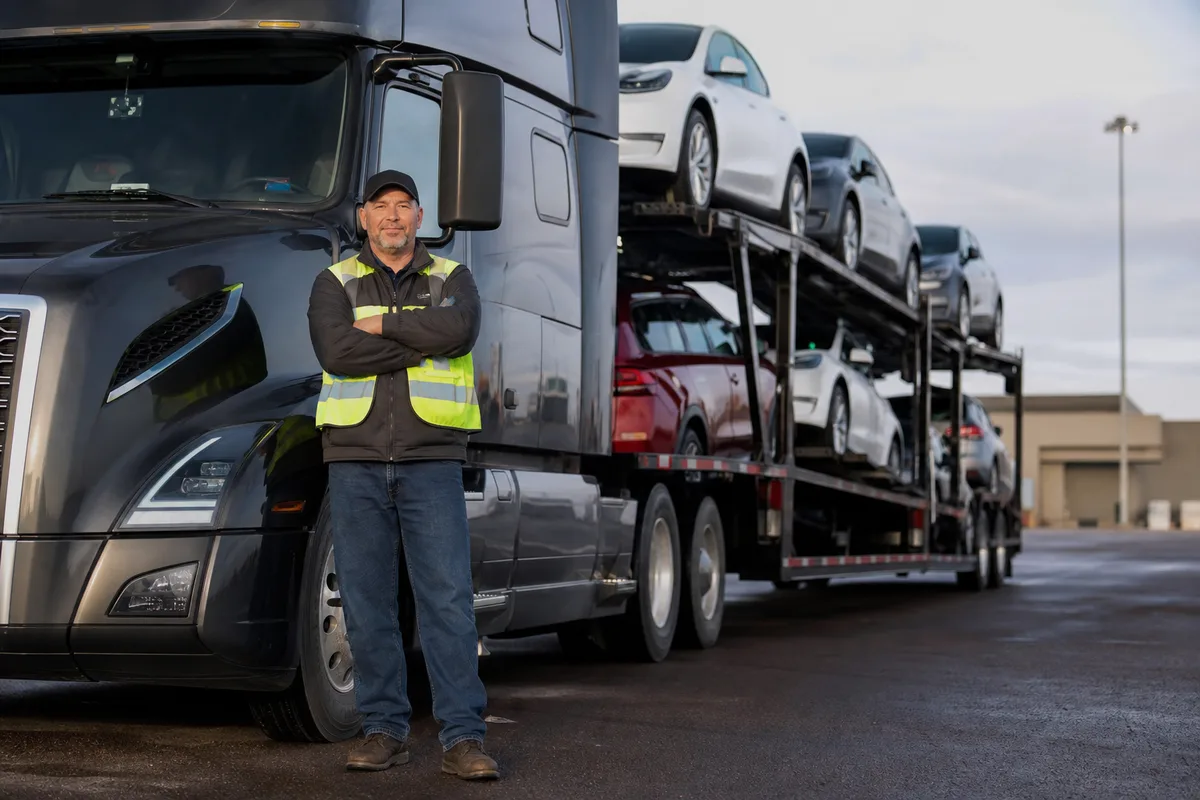 Professional CDL driver beside auto transport truck
